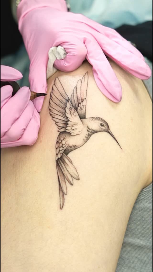22 Delicate Tattoo Ideas for Light, Fine-Line Ink 11 A hummingbird tattoo being applied to skin by a person wearing pink gloves.