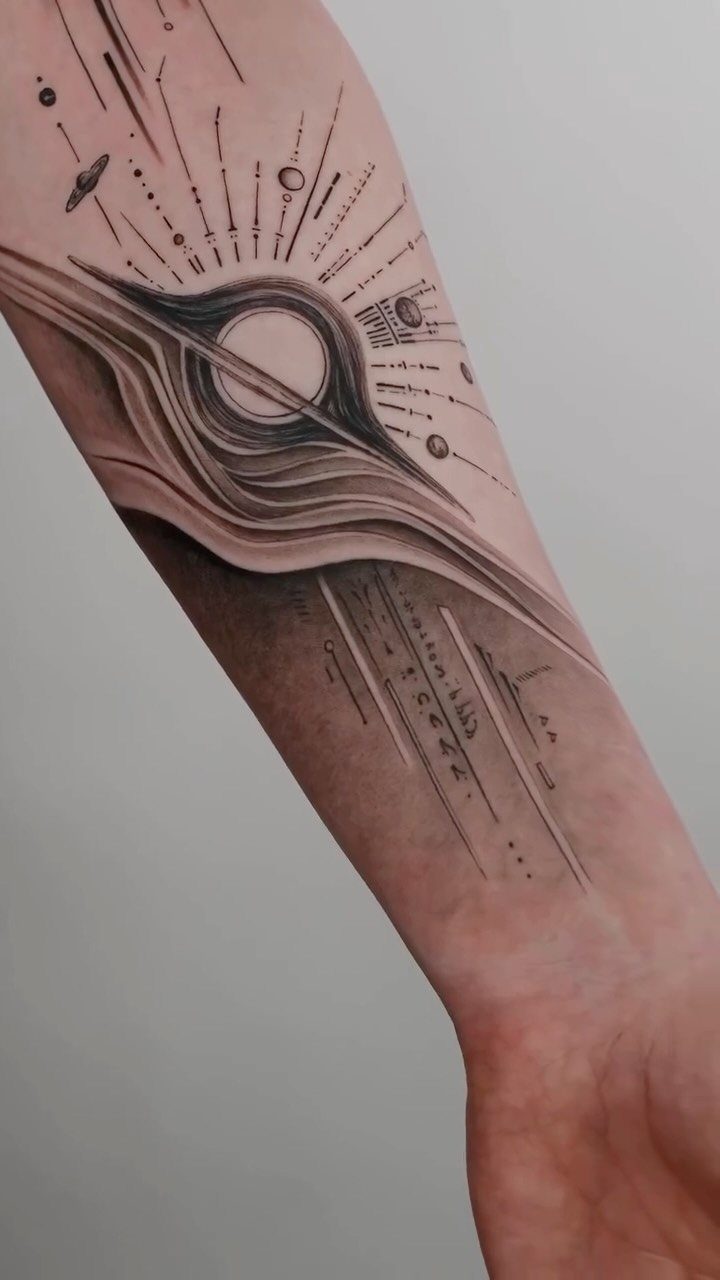 25 Space Themed Tattoos from Watercolor Cats to Black Holes 22 A detailed black and grey space themed tattoo on a person's forearm featuring a black hole.
