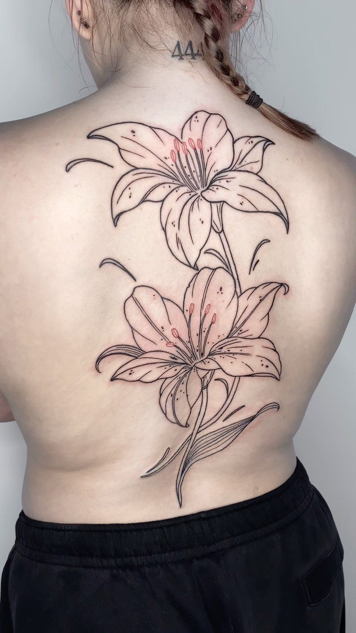 Tattoo Style Back: 9 Designs That Use the Whole Canvas 4 Two large lily flowers with pink shading tattooed vertically along a person's spine.