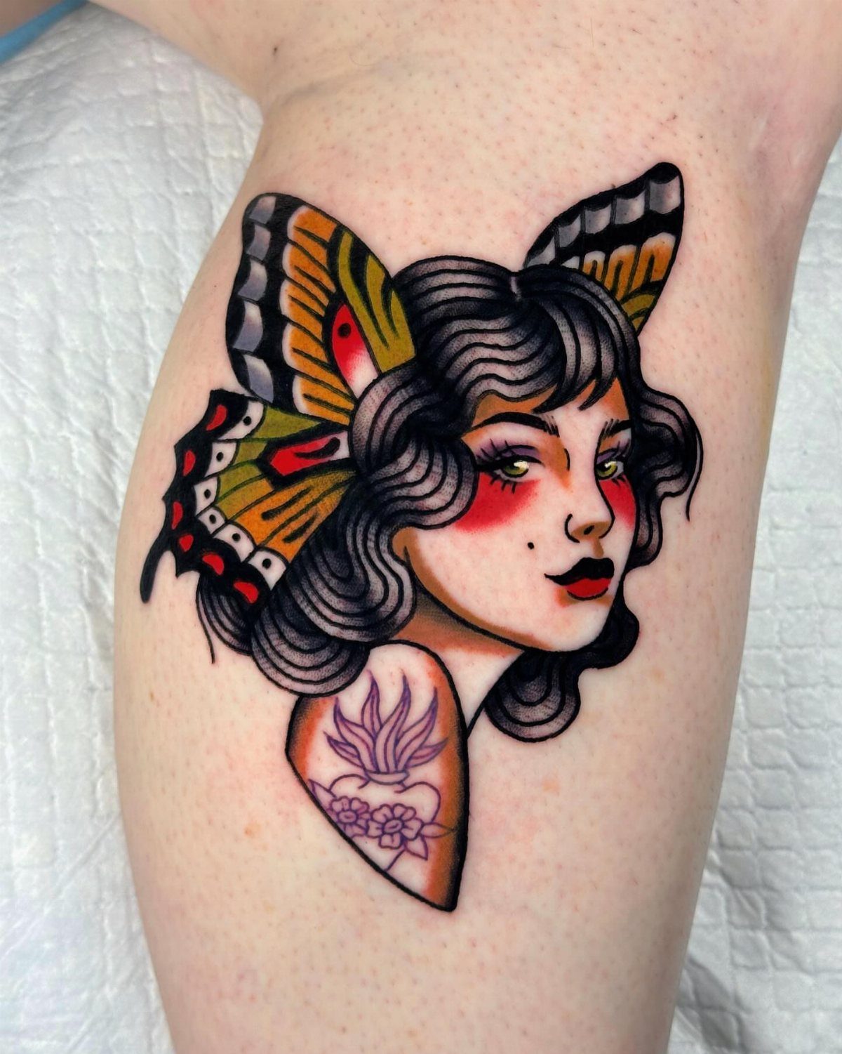 Traditional Lady Tattoo: 9 Designs for Every Style 9 A traditional style tattoo of a woman's face framed by colorful butterfly wings on skin.