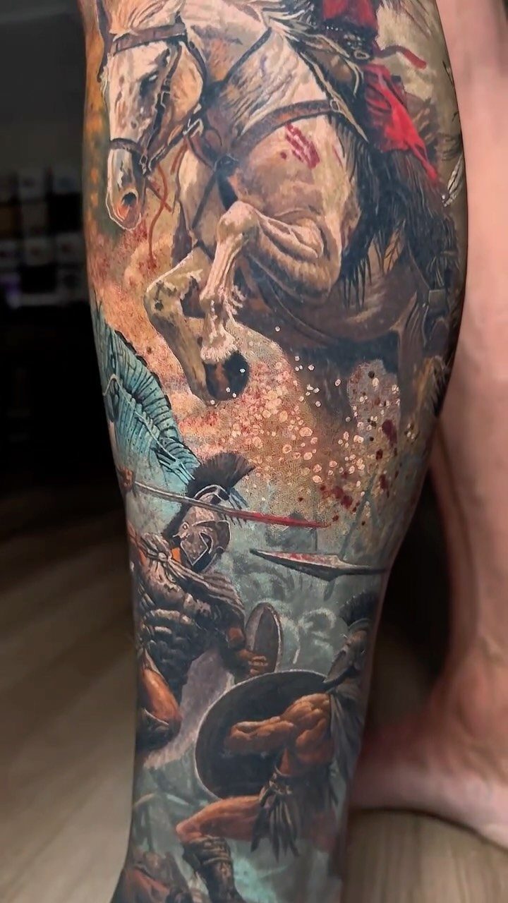 Leg Tattoo Base: 14 Placements from Ankle to Full Sleeve for 2026 2 A large, detailed tattoo of a charging horse and ancient warriors covering a person's lower leg.