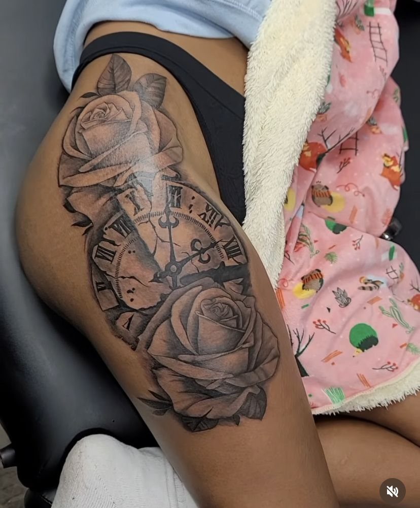 Thigh Tattoos for Women: 8 Ideas from Floral to Geometric Art 9 A large black and grey tattoo of a clock and roses on a woman's thigh.