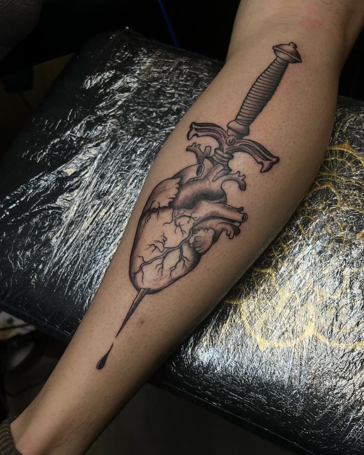 15 Tattoo Placement Heart Ideas for Meaning and Style 7 Anatomical heart tattoo being pierced by a dagger on a person's forearm.
