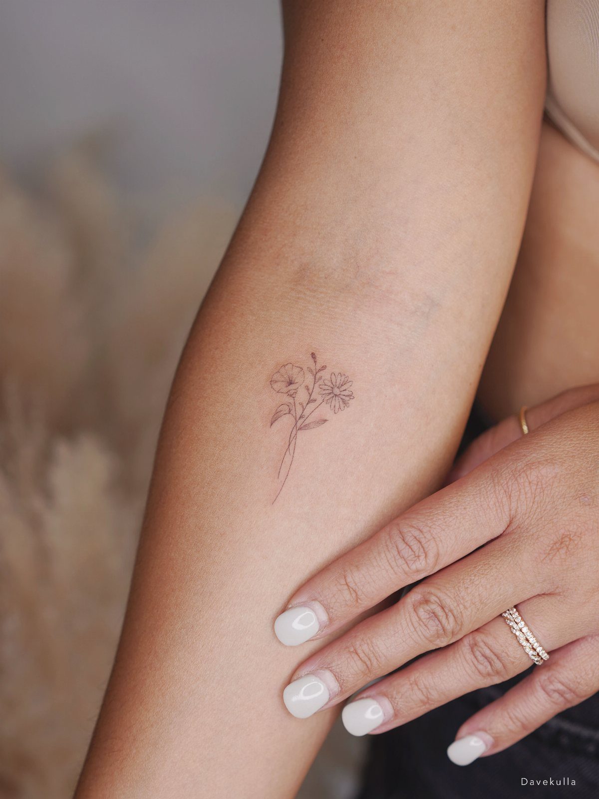 22 Delicate Tattoo Ideas for Light, Fine-Line Ink 3 A delicate fine-line flower tattoo on a person's forearm with white manicured nails.