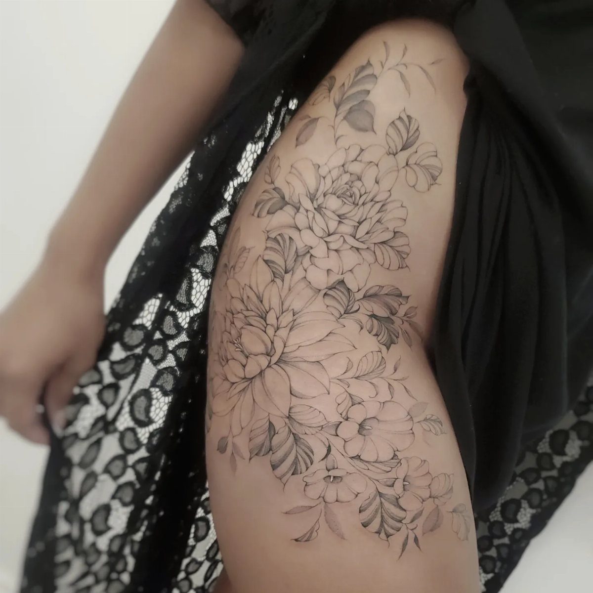 A large black and grey floral tattoo covering a person's hip and upper thigh.