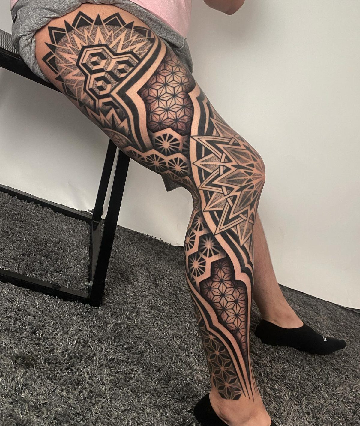 Leg Tattoo Base: 14 Placements from Ankle to Full Sleeve for 2026 10 A person's leg displaying a large, detailed black and grey geometric tattoo from thigh to ankle.