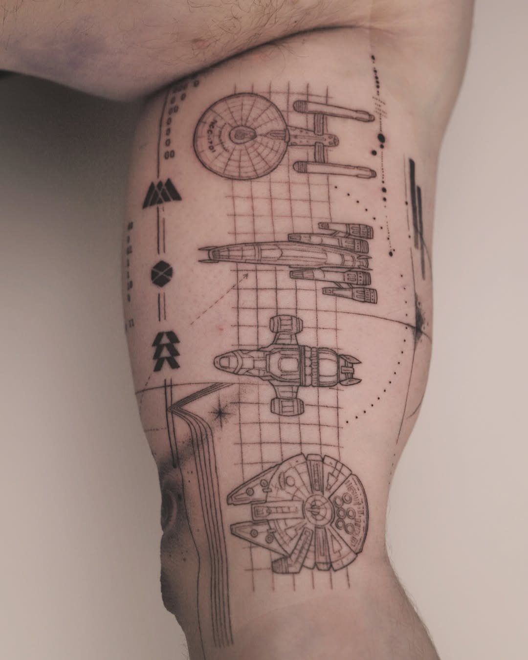 25 Space Themed Tattoos from Watercolor Cats to Black Holes 8 Black ink geometric spacecraft tattoos on a person's leg with fine grid lines and celestial details.