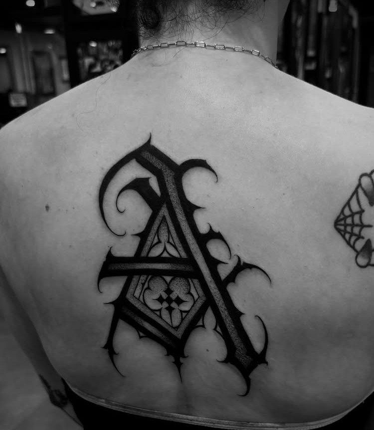 Tattoo Style Back: 9 Designs That Use the Whole Canvas 10 A large black ink gothic letter A tattoo on a person's upper back.