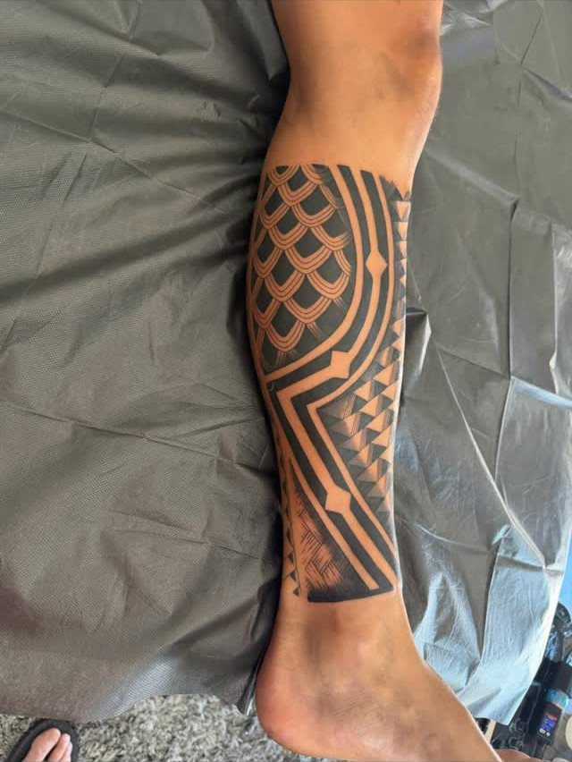 Polynesian Tattoo Pattern: 16 Island Styles From Marquesan to Maori 5 A person's lower leg featuring a large black geometric Polynesian style tattoo.