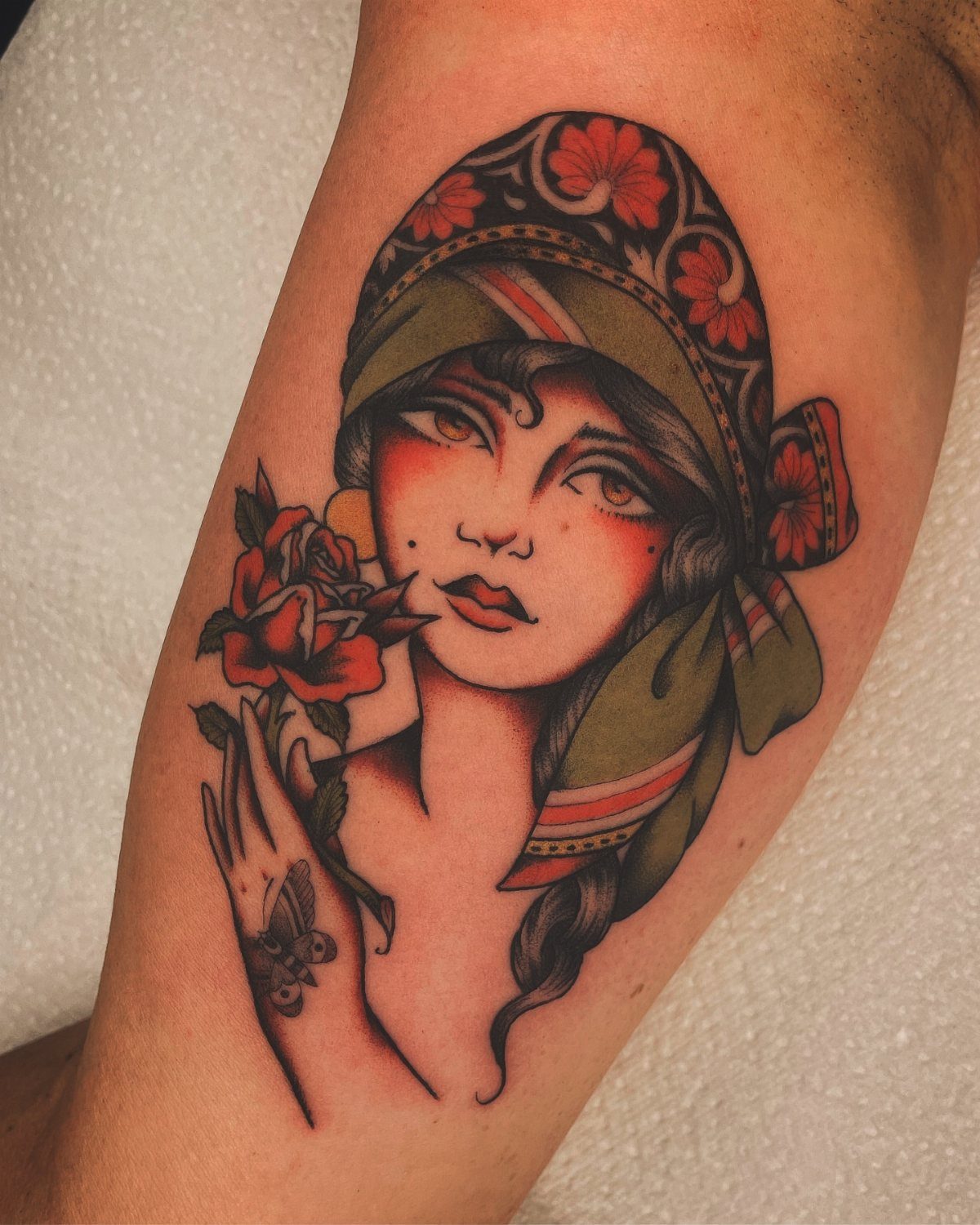 Traditional Lady Tattoo: 9 Designs for Every Style 6 A traditional tattoo of a woman with a headscarf holding a red rose on skin.