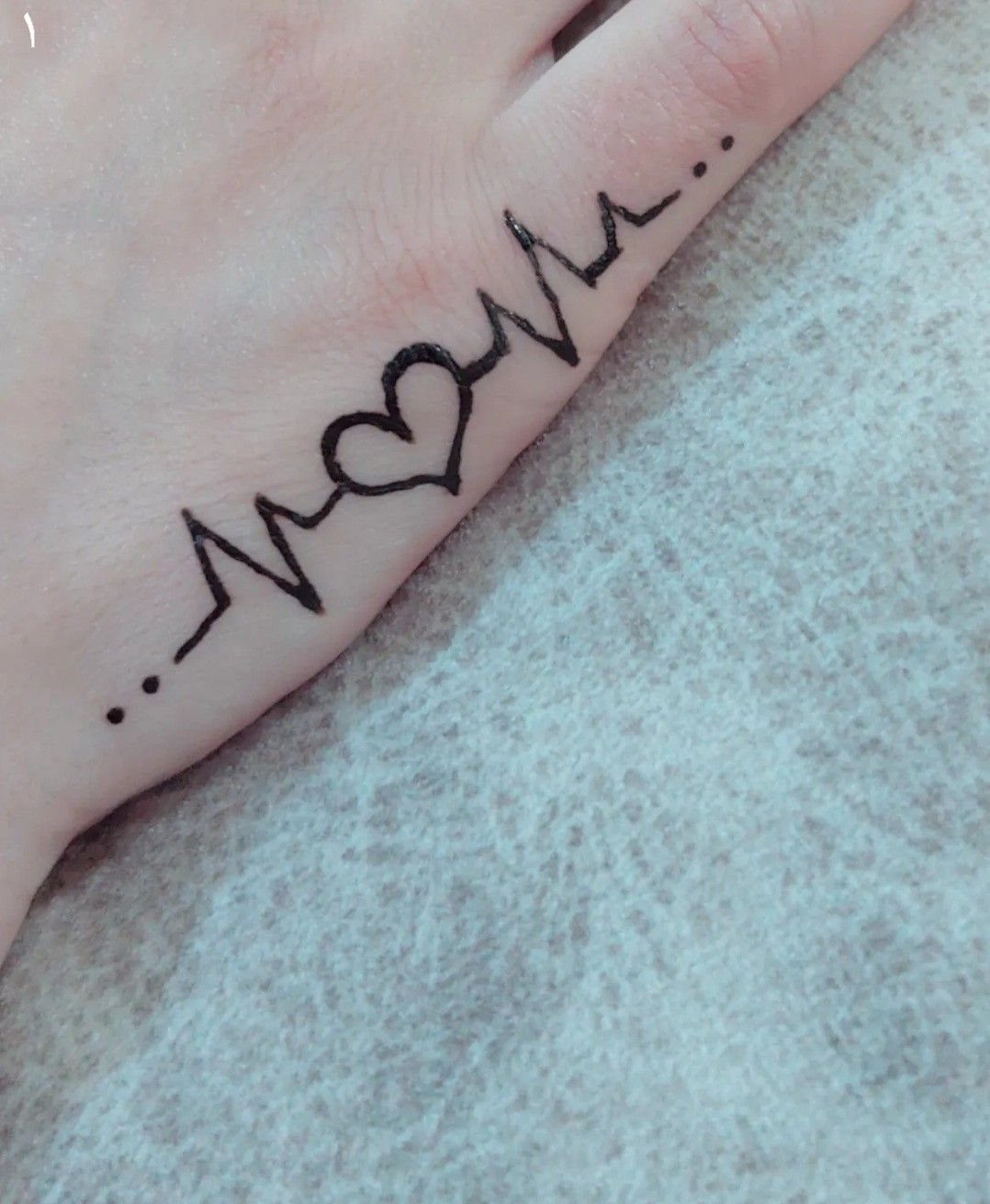 Tattoo Henna Simple: 9 Easy Designs for Hands, Fingers & Shoulders 9 A black ink heartbeat line tattoo with a heart shape on a person's finger.