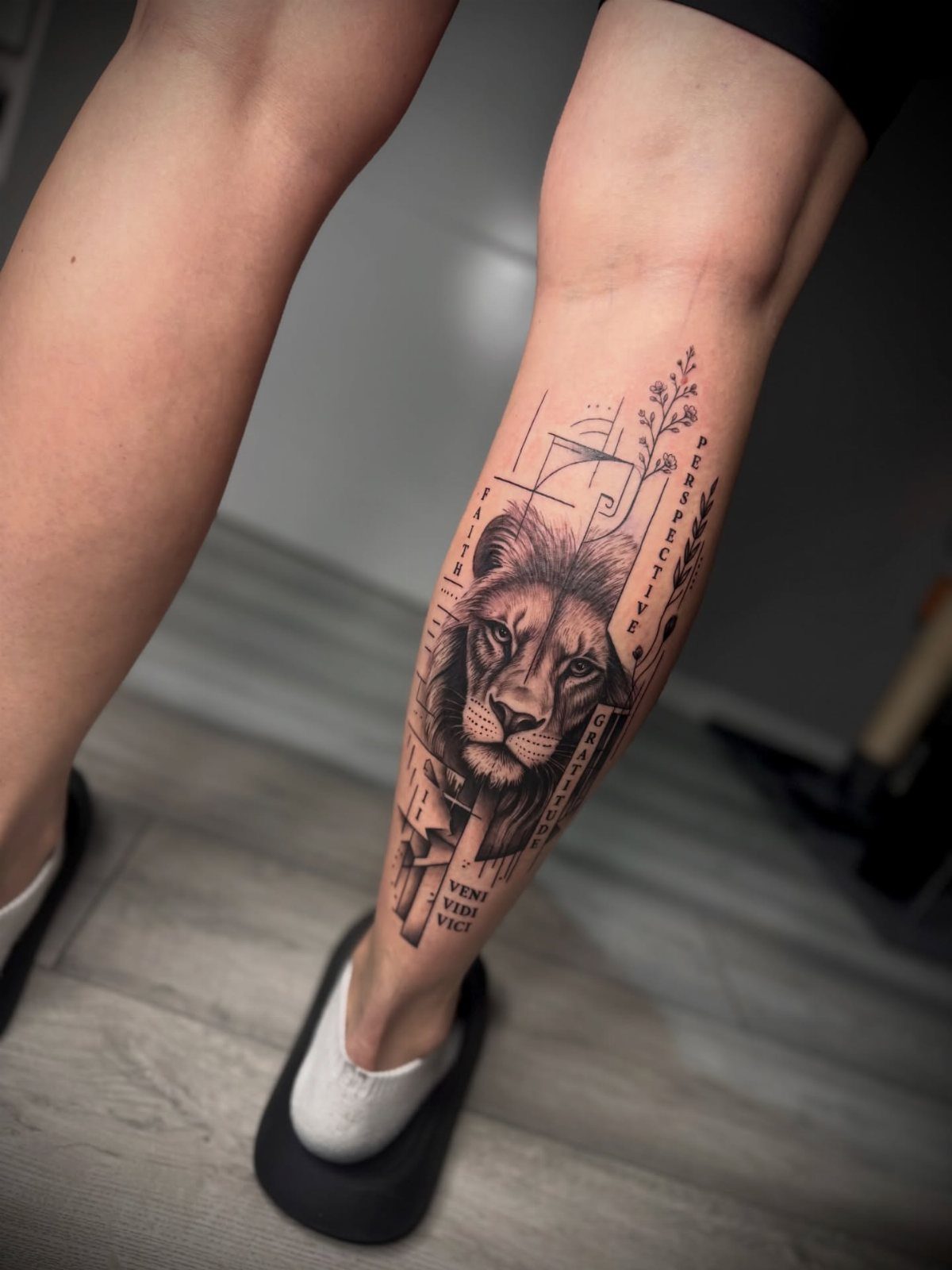 Leg Tattoo Base: 14 Placements from Ankle to Full Sleeve for 2026 12 A realistic black and grey lion portrait tattoo on a person's lower leg.
