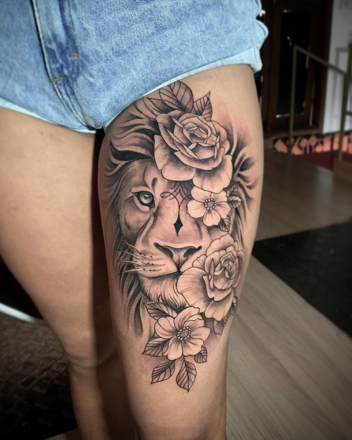 Thigh Tattoos for Women: 8 Ideas from Floral to Geometric Art 8 A large black and grey lion tattoo with roses on a woman's thigh.