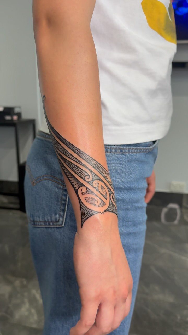 Polynesian Tattoo Pattern: 16 Island Styles From Marquesan to Maori 4 A person's forearm displaying a large black Polynesian tattoo with intricate spiral patterns.
