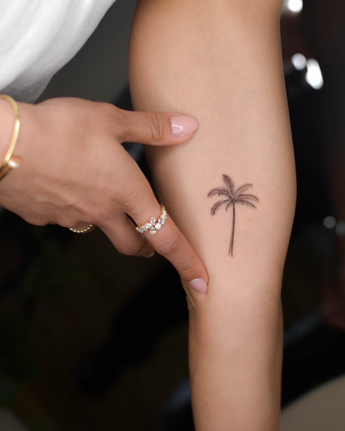 Fine Line Travel Tattoo: 10 Designs That Stay Light on Skin 6 A small fine line palm tree tattoo on a person's forearm.