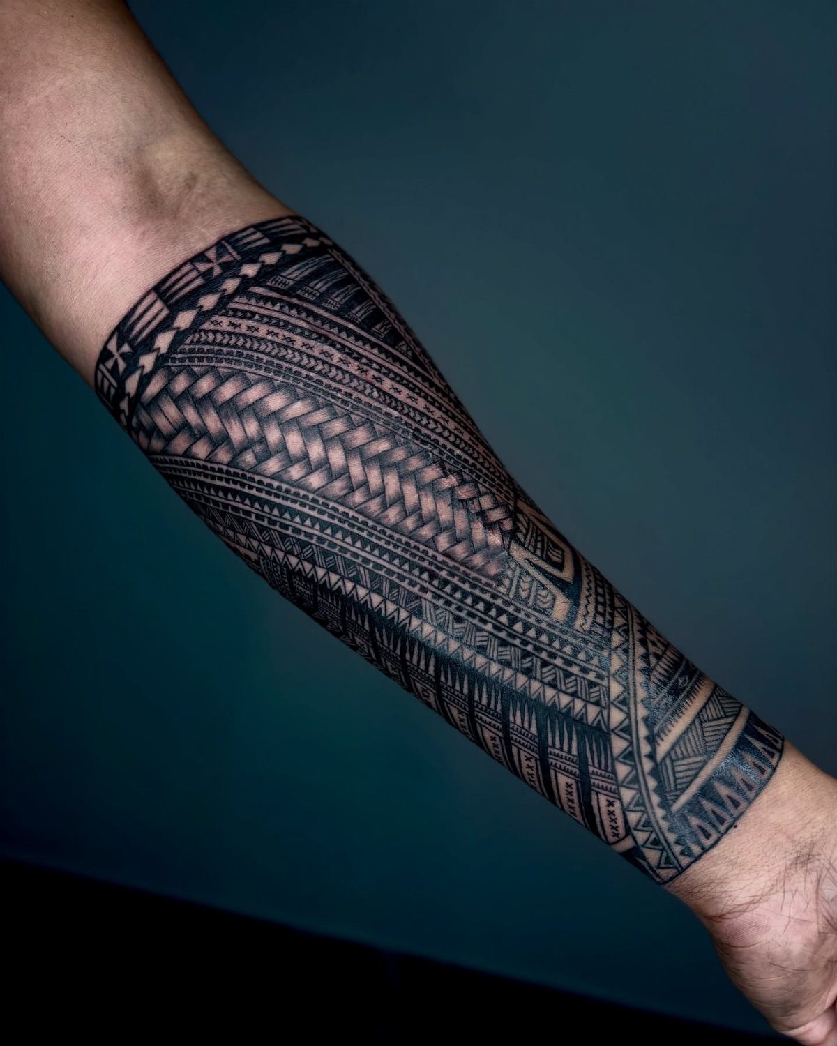A detailed black ink Polynesian tribal tattoo covering a person's entire forearm.