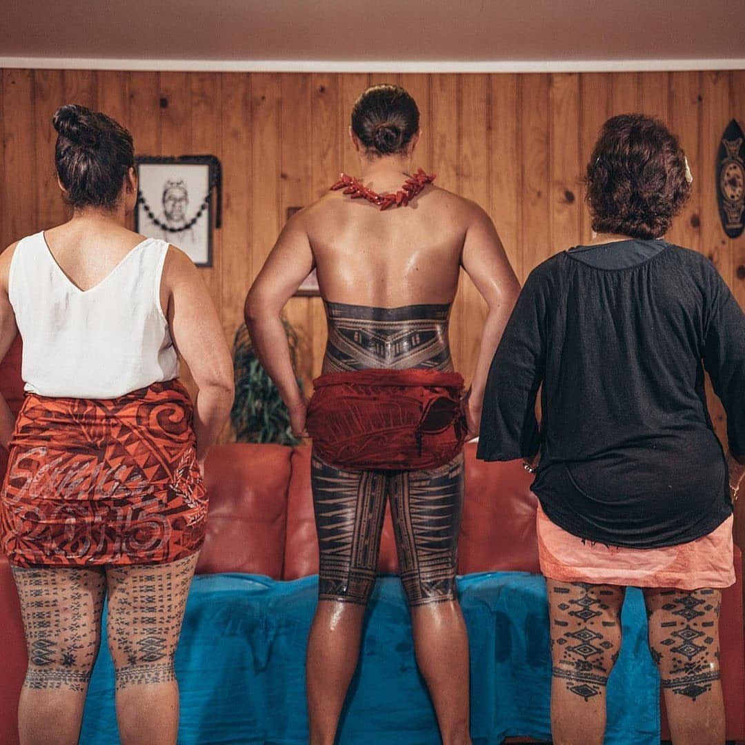 Polynesian Tattoo Pattern: 16 Island Styles From Marquesan to Maori 3 Three people standing with their backs turned, showing intricate Polynesian geometric tattoos on their legs and lower backs.