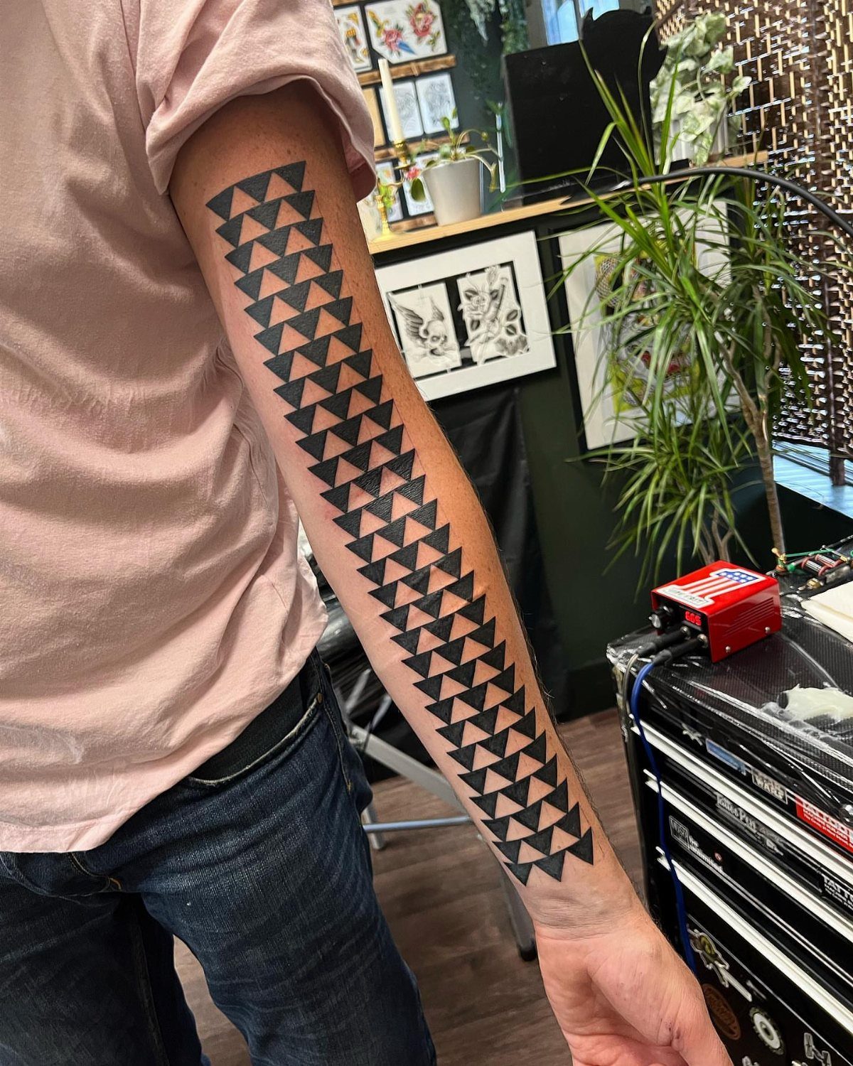 Polynesian Tattoo Pattern: 16 Island Styles From Marquesan to Maori 12 A person's arm displaying a large black Polynesian tattoo featuring repeating triangular shark tooth patterns.