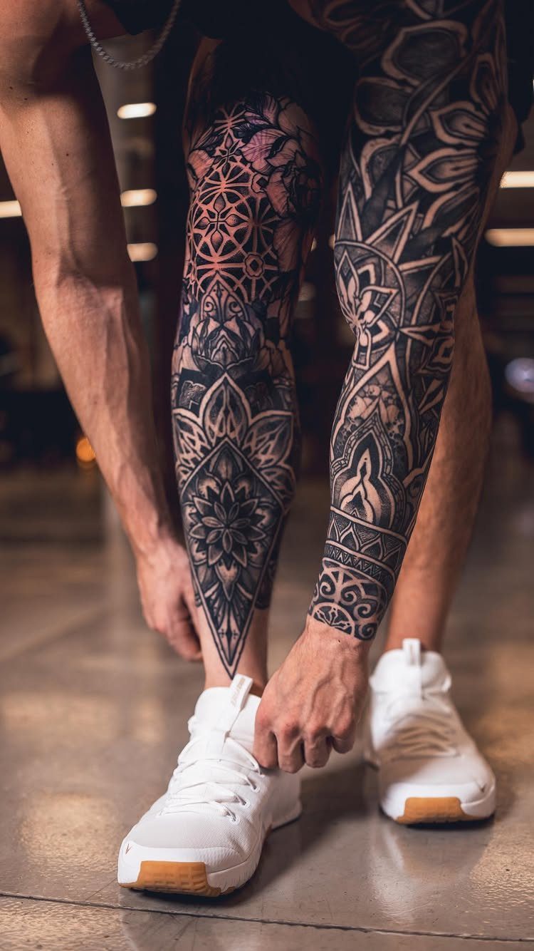 Leg Tattoo Base: 14 Placements from Ankle to Full Sleeve for 2026 6 Person bending down to tie white sneakers, revealing detailed black ink geometric leg tattoos.