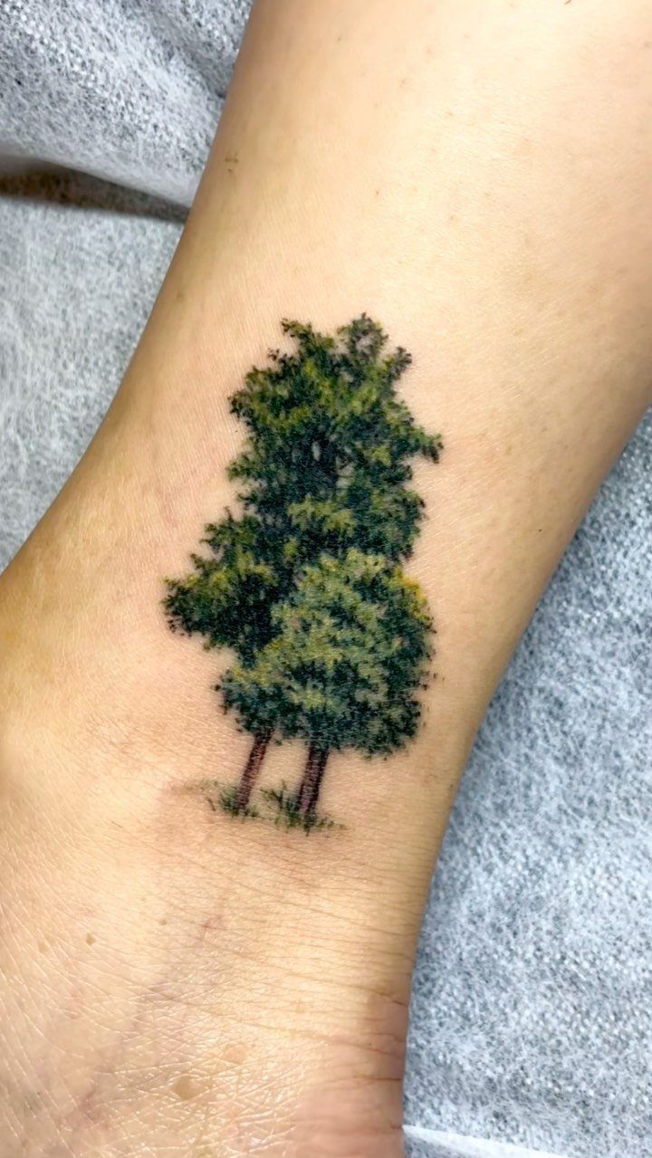 22 Delicate Tattoo Ideas for Light, Fine-Line Ink 10 A small, detailed green tree tattoo on a person's pale skin.