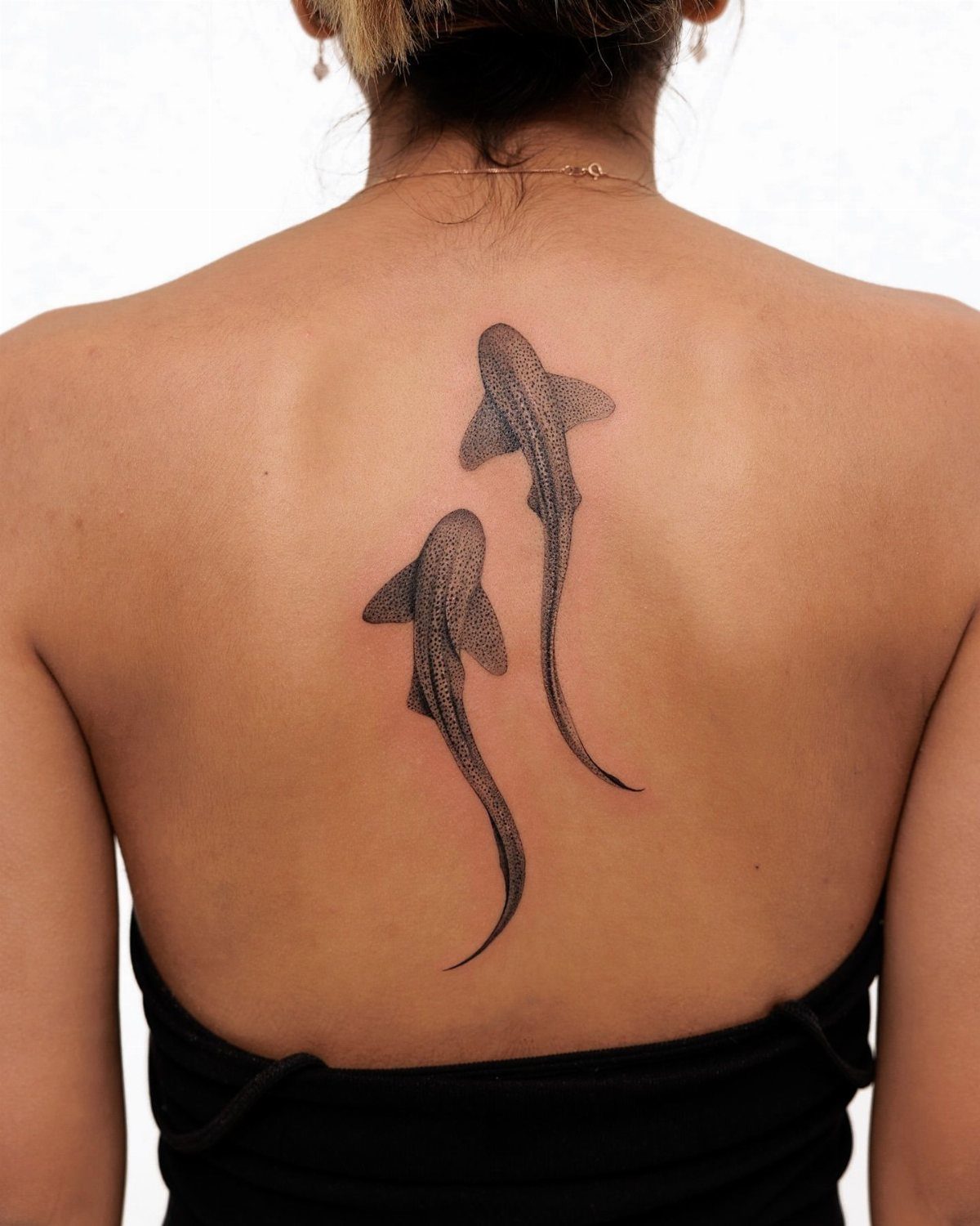 7 Shark Spine Tattoo Ideas for Vertical Oceans 3 Two realistic black ink shark tattoos swimming vertically down a person's spine.