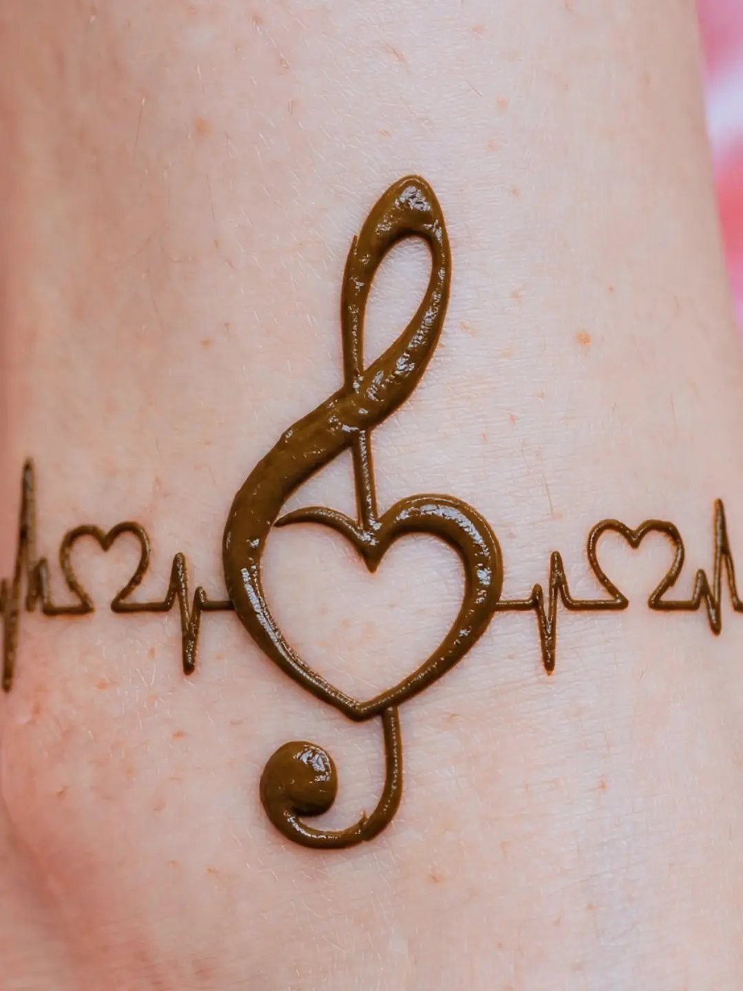 Henna design on skin featuring a treble clef, heart, and heartbeat line.