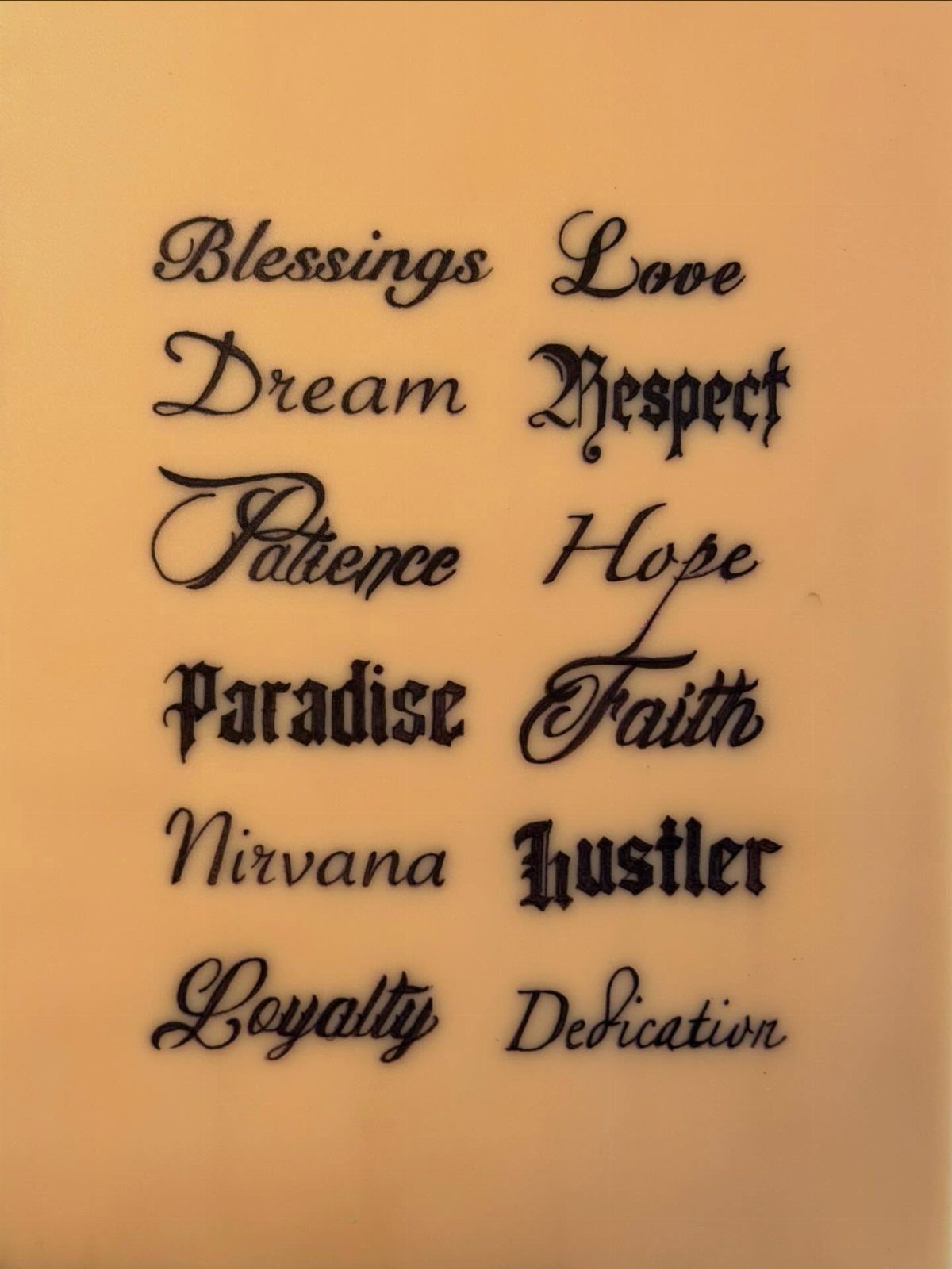 Various words written in different black ink calligraphy and gothic tattoo styles on a plain background.