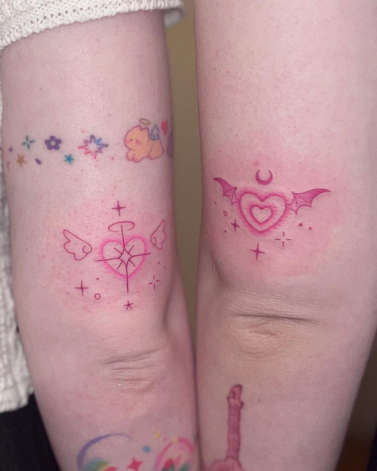 22 Delicate Tattoo Ideas for Light, Fine-Line Ink 4 Two arms displaying several small, pink, fine-line tattoos including winged hearts and stars.