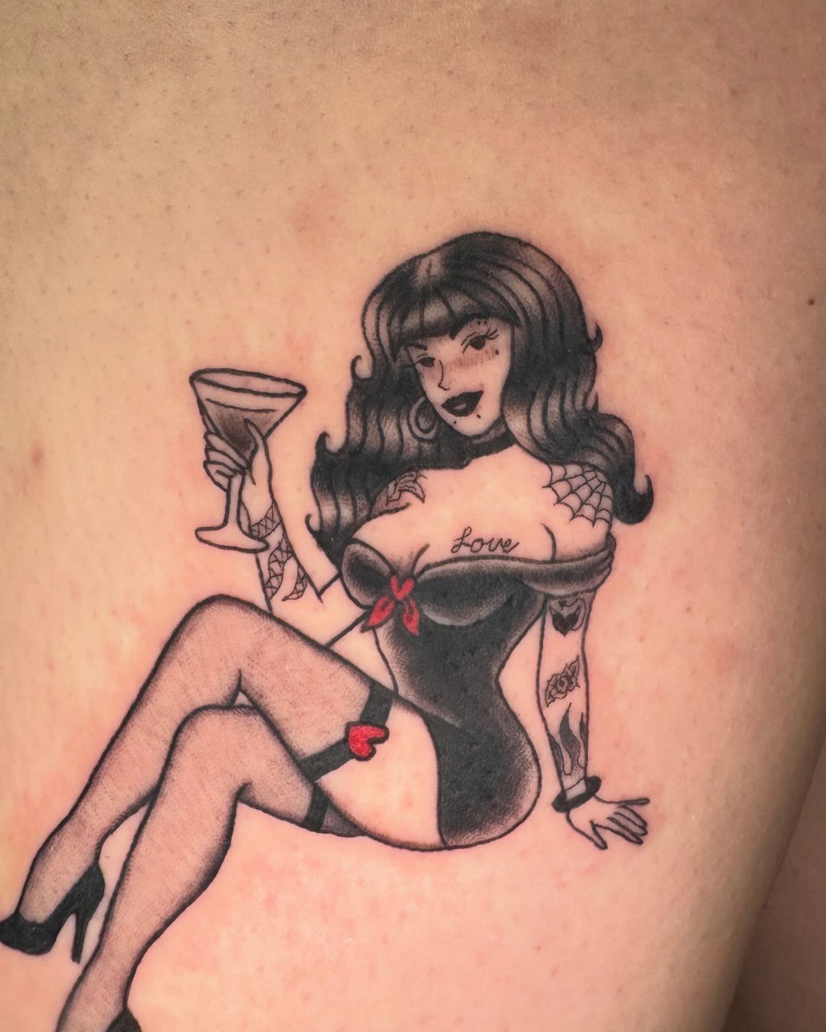 A black and red American traditional tattoo of a woman holding a cocktail glass.