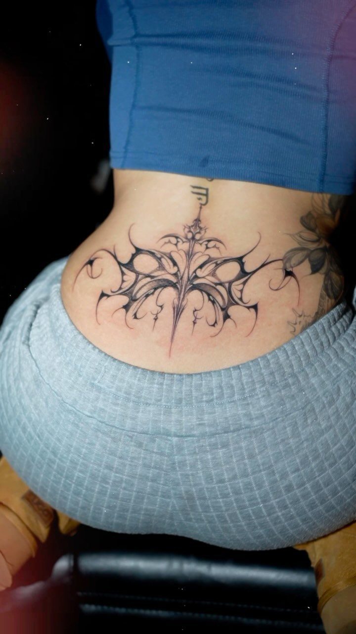 A large black tribal butterfly tattoo on a person's lower back and side hip.