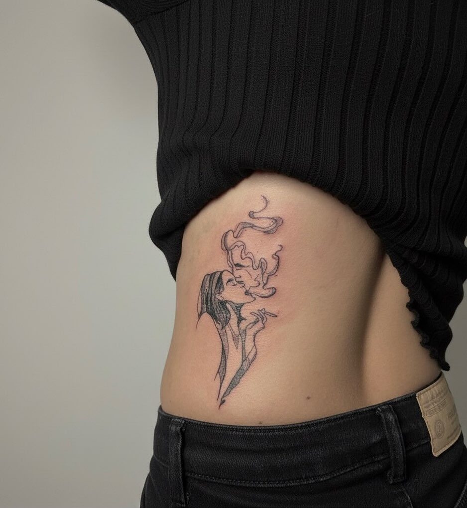 A black ink profile tattoo of a woman blowing smoke on a person's ribcage.